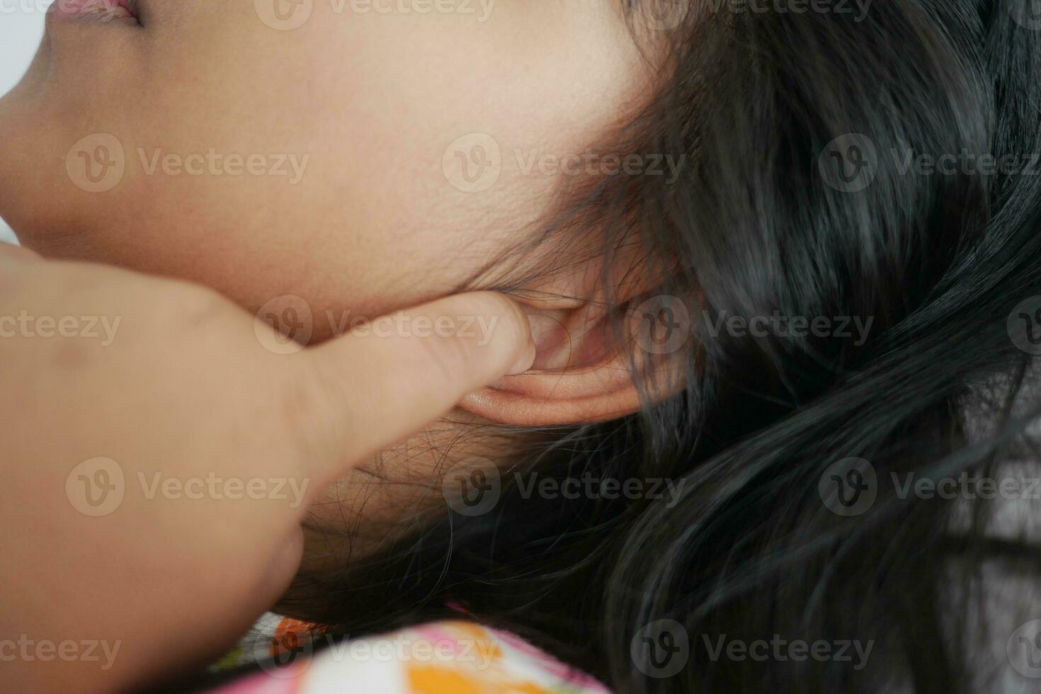 child having ear pain touching his painful ear , photo