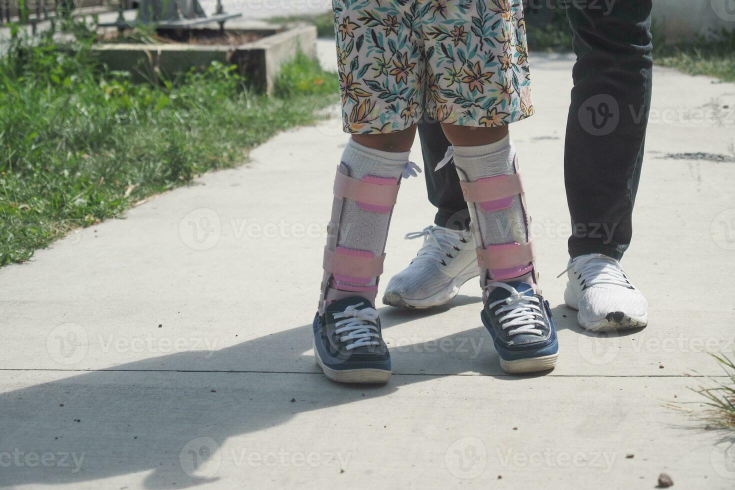 niño cerebral parálisis invalidez con piernas ortesis caminando al aire libre foto