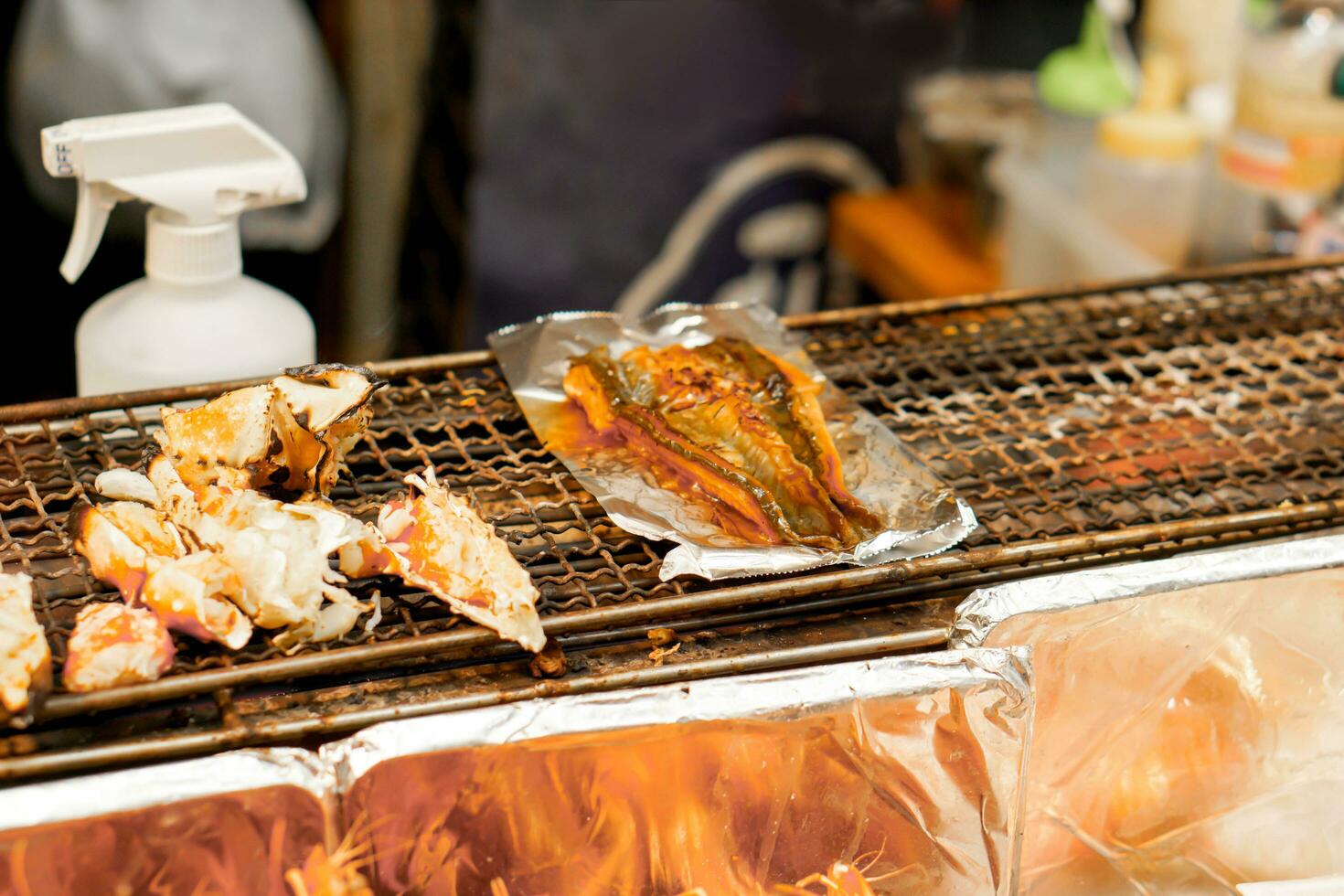 Closeup burned King crab legs and grilled Japanese eels fish on stove to sale for customer at Kuromon market, Osaka, Japan. Burned King crab legs and grilled Japanese eels fish is popular in tourist. photo