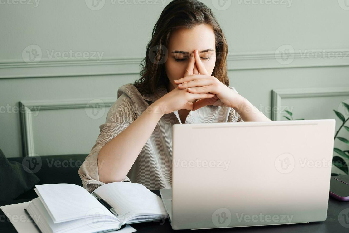 An unhappy tired woman with a laptop suffering from overwork, blood pressure, migraines and stress photo