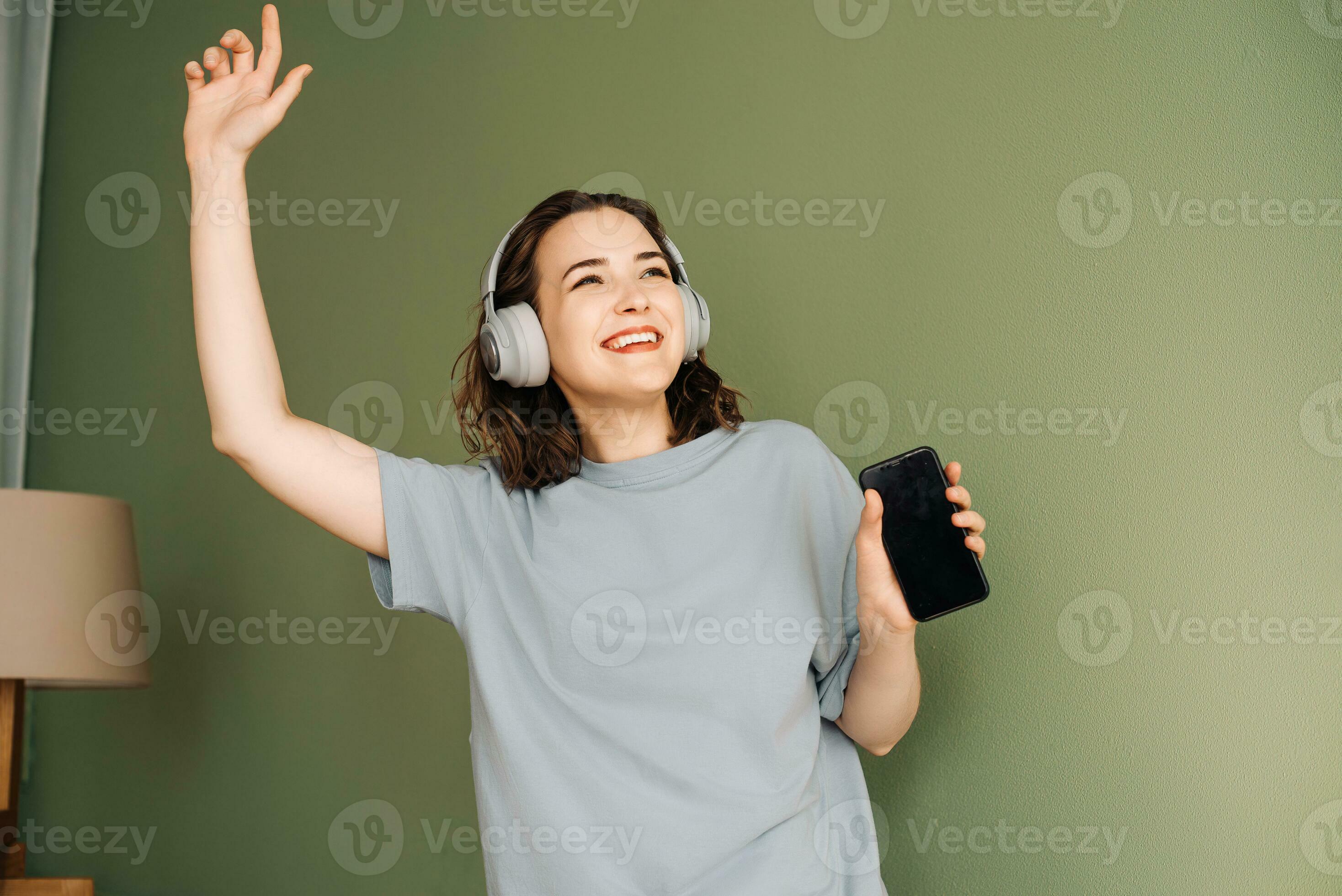 Happy young woman wearing wireless headphones listening to music