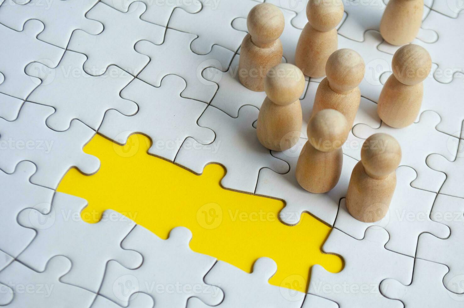 Missing jigsaw puzzle with wooden dolls. Representing hiring and copy space. photo
