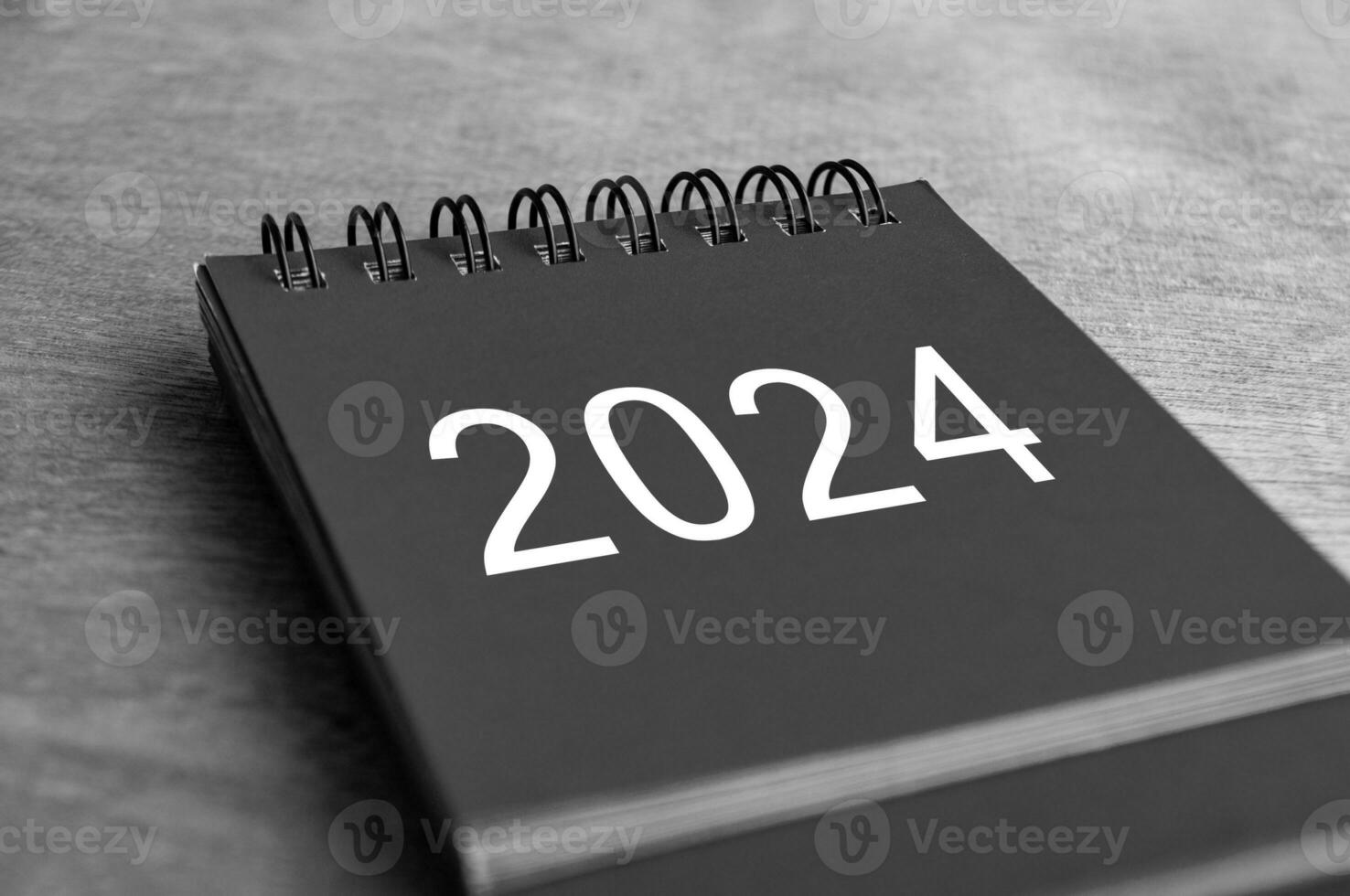 Black and white Year 2024 desk calendar on wooden desk. New Year and calendar concept photo