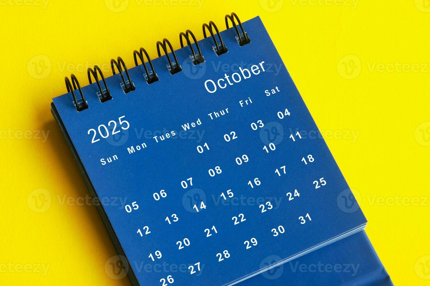 October 2025 blue desk calendar on yellow cover background. photo