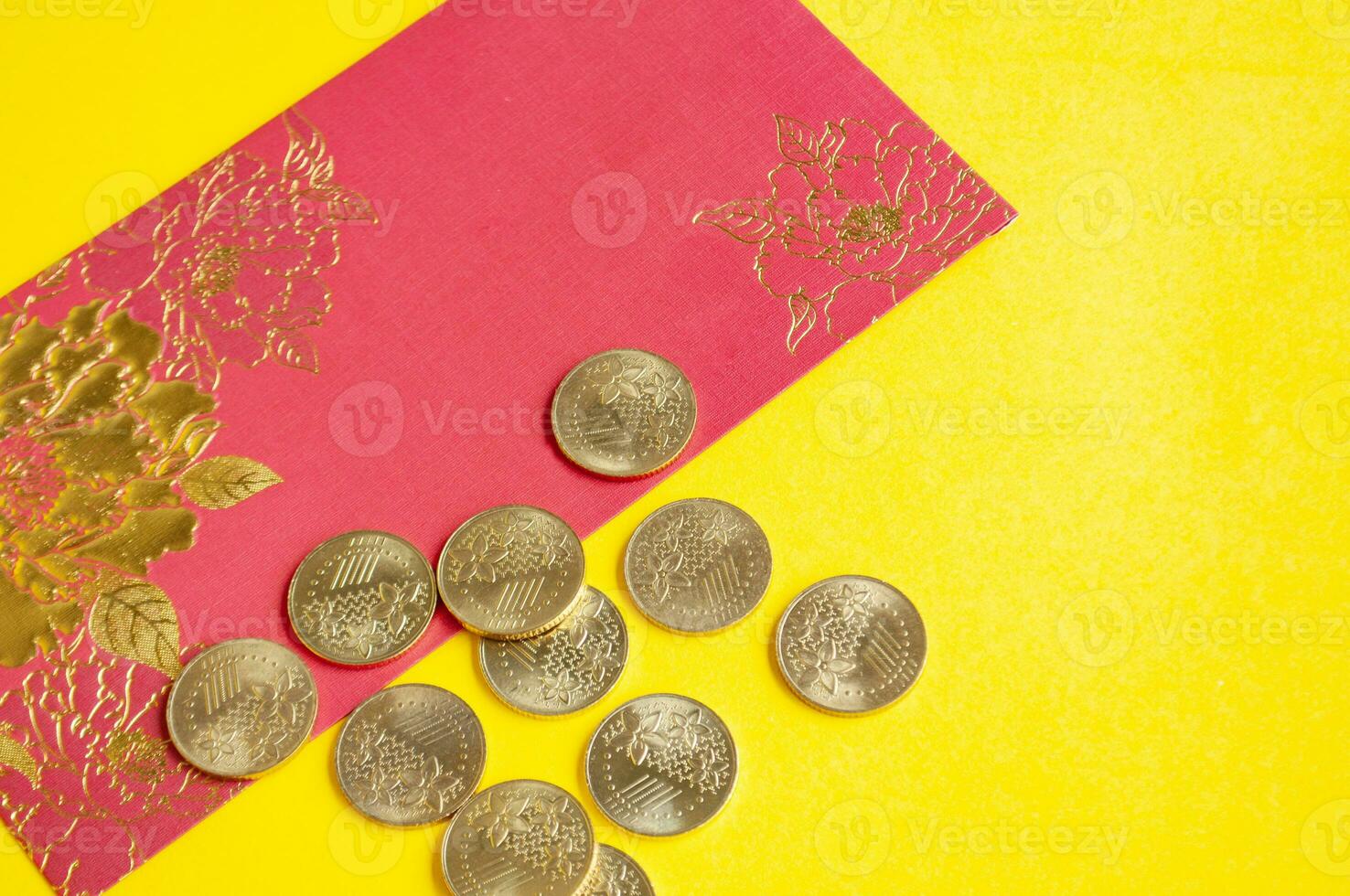 Top view of Chinese New Year red packets and golden coins on yellow cover background photo