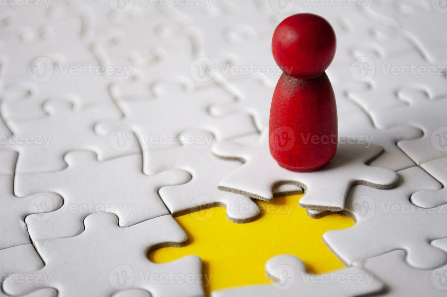 Red wooden doll on top of jigsaw with missing jigsaw puzzle. Hiring and employment concept photo