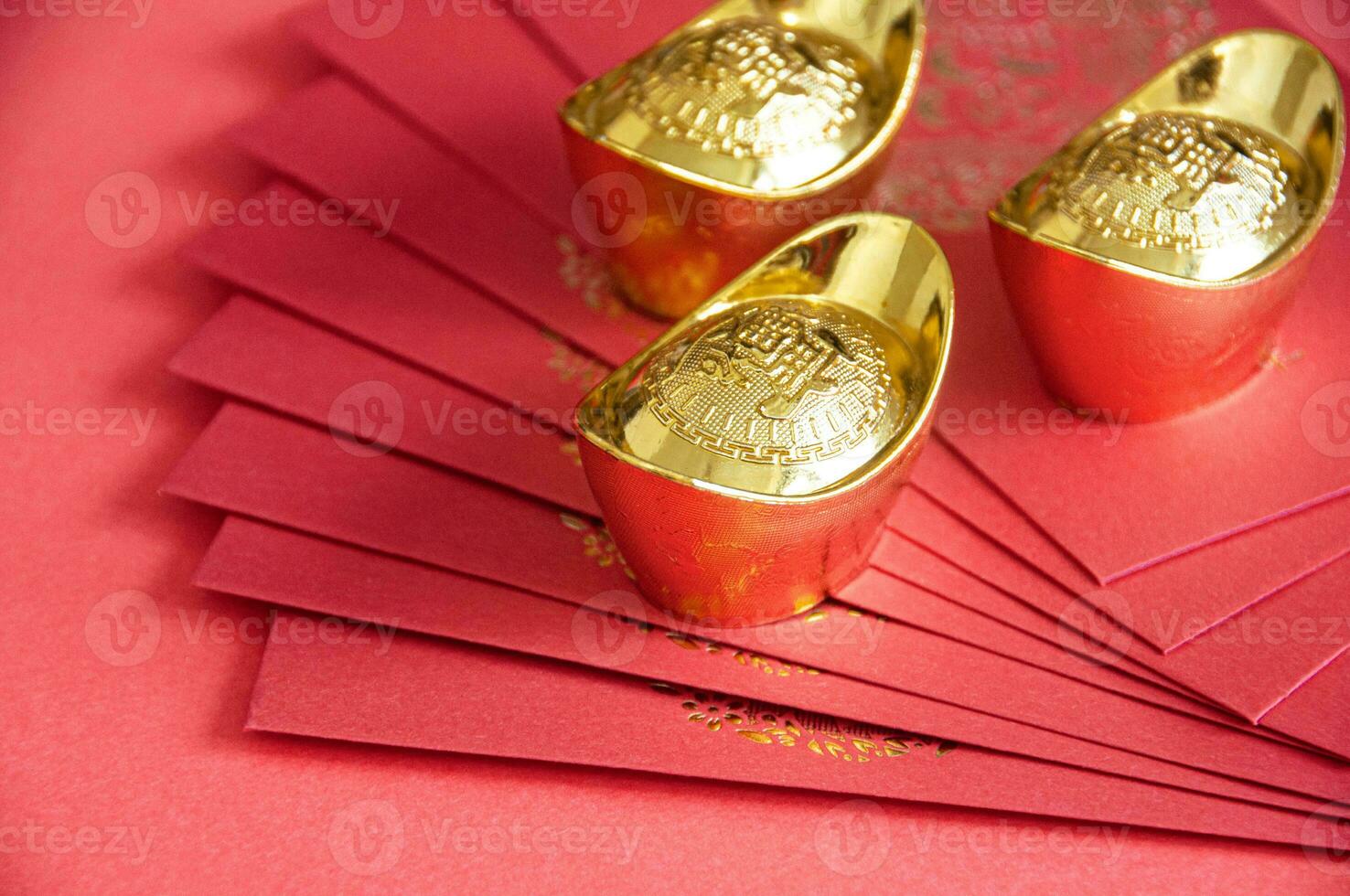 Red envelope and golden ingots on red cover background with Chinese New Year wishes photo