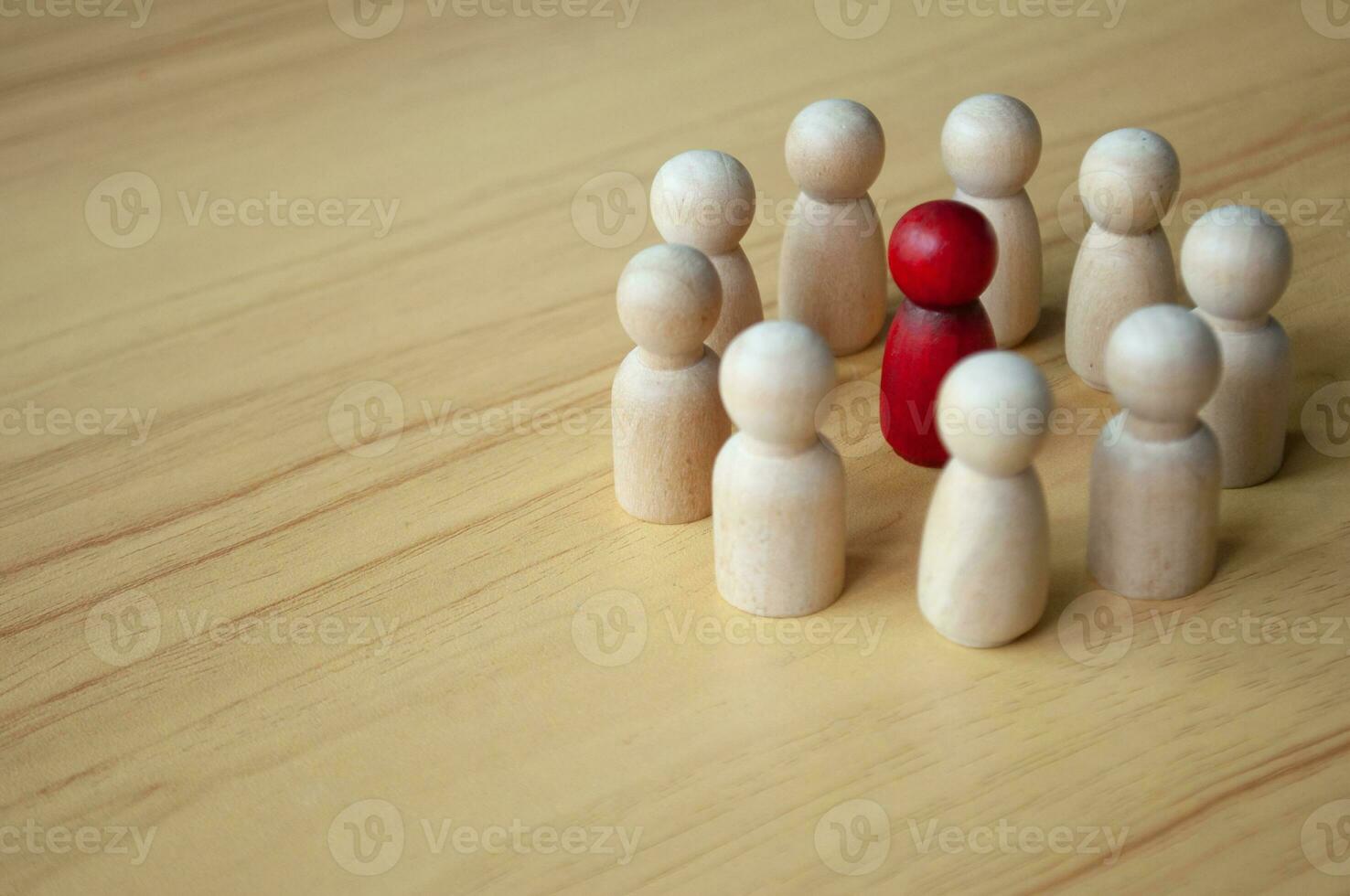 Red wooden doll surrounded by other dolls. Representing either discussion, leadership or harassment photo