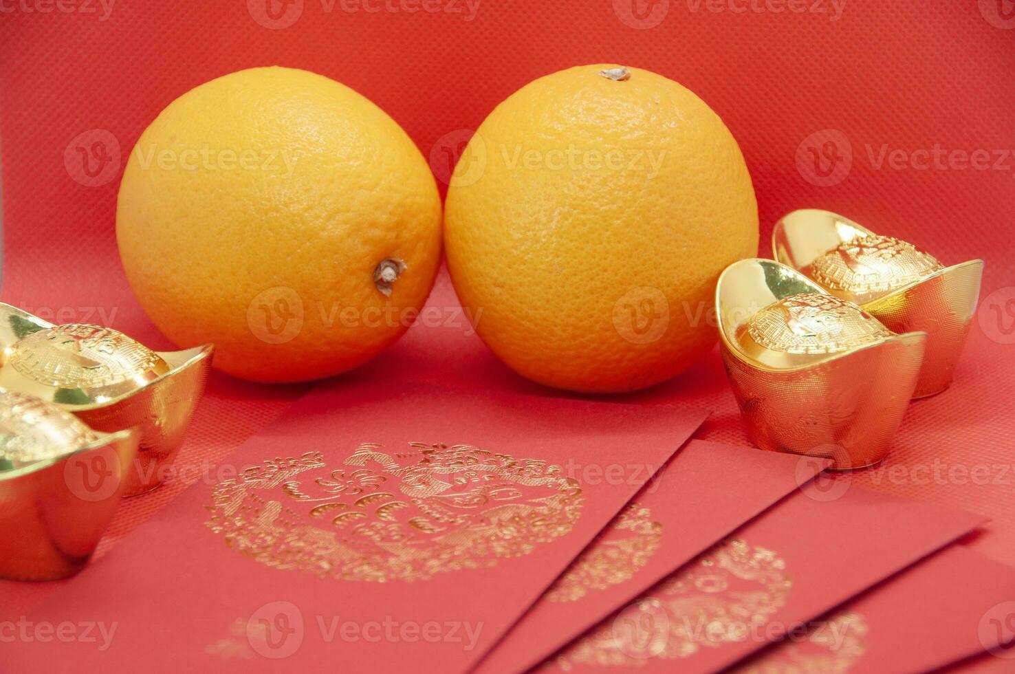 Red envelope, oranges and golden ingots on red cover background with Chinese New Year wishes photo