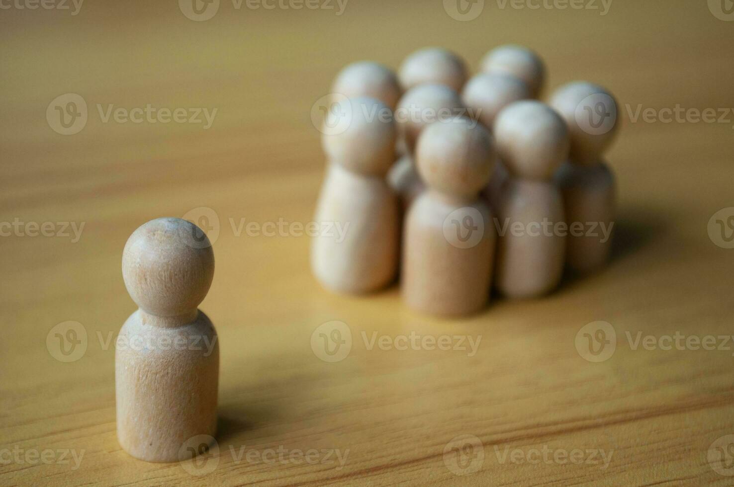 A single wooden doll separated by other dolls. Representing either leadership or isolation. photo