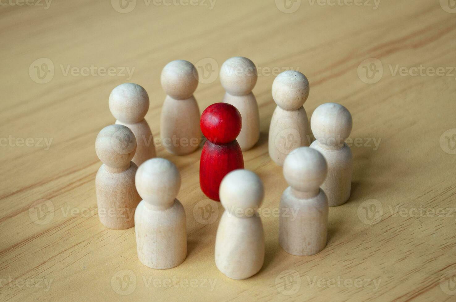 Close up of red wooden doll surrounded by other dolls. Representing either leadership or harassment photo
