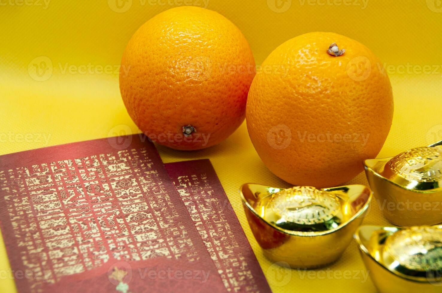 Chinese New Year decoration with oranges, dark red packets and gold ingots on yellow cover background. Chinese festive season concept and copy space. photo
