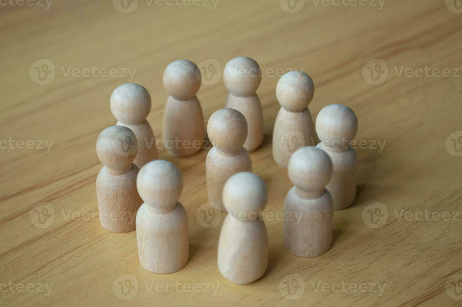 A wooden doll surrounded by other dolls. Representing either leadership or harassment. photo