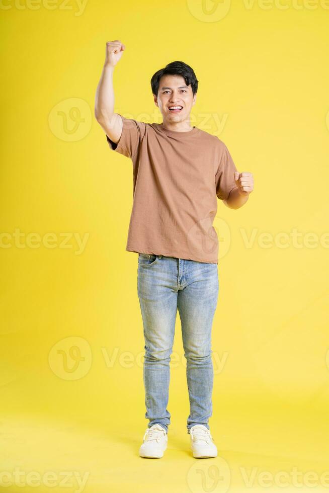 Portrait of asian man posing on yellow background photo