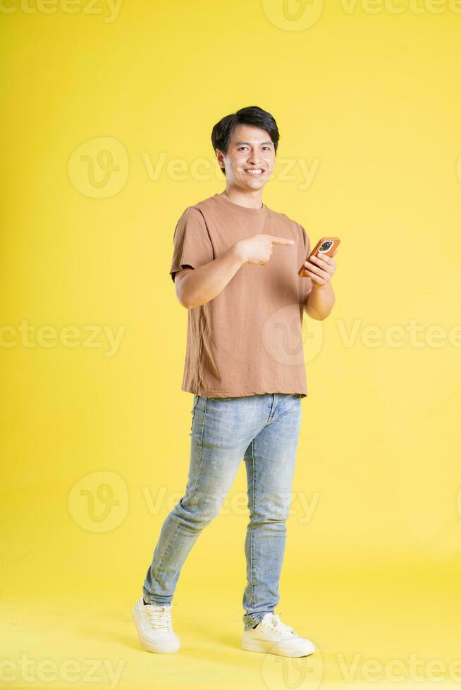 Portrait of asian man posing on yellow background photo