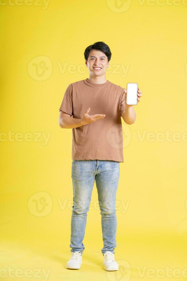 Portrait of asian man posing on yellow background photo