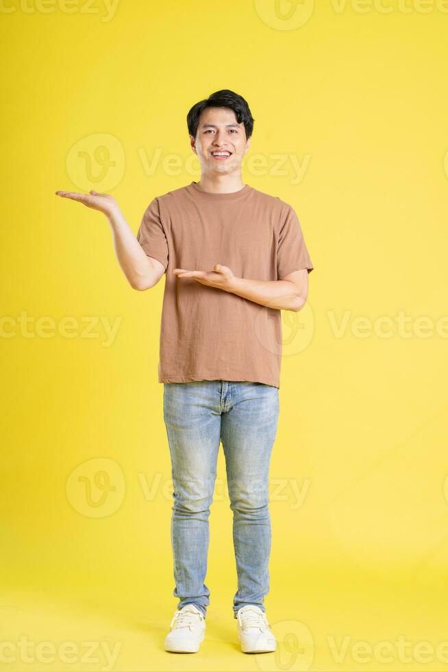 Portrait of asian man posing on yellow background photo