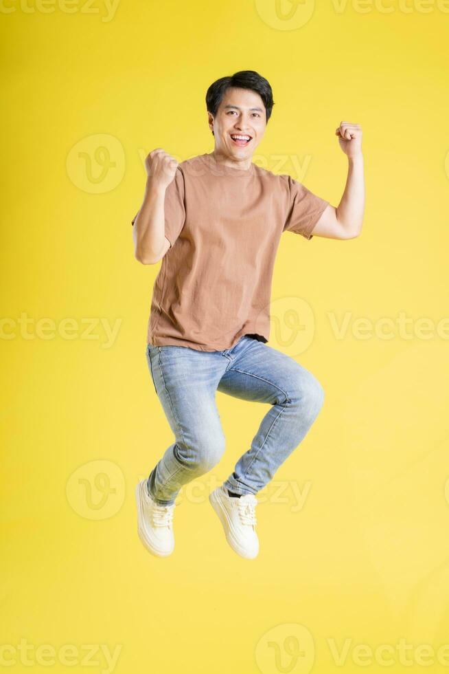 Portrait of asian man posing on yellow background photo