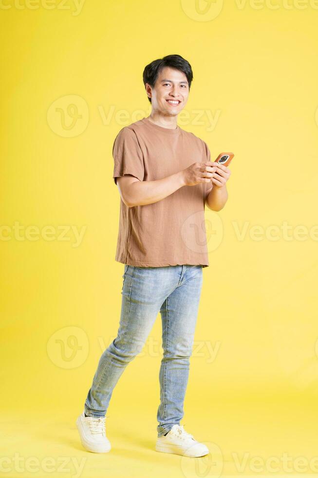 Portrait of asian man posing on yellow background photo