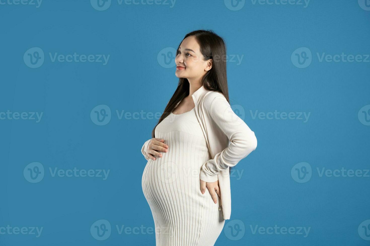 retrato de embarazada asiático mujer, aislado en azul antecedentes foto