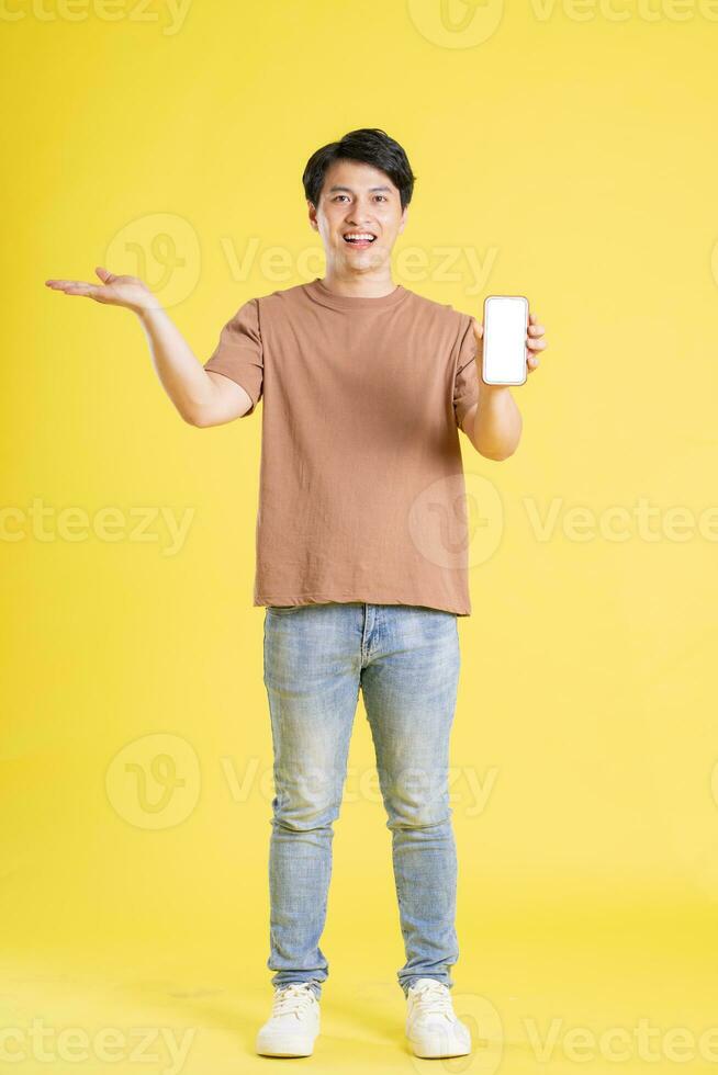 Portrait of asian man posing on yellow background photo