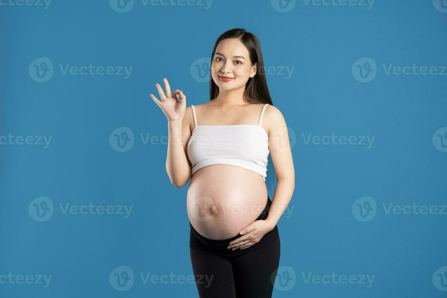 retrato de embarazada asiático mujer, aislado en azul antecedentes foto