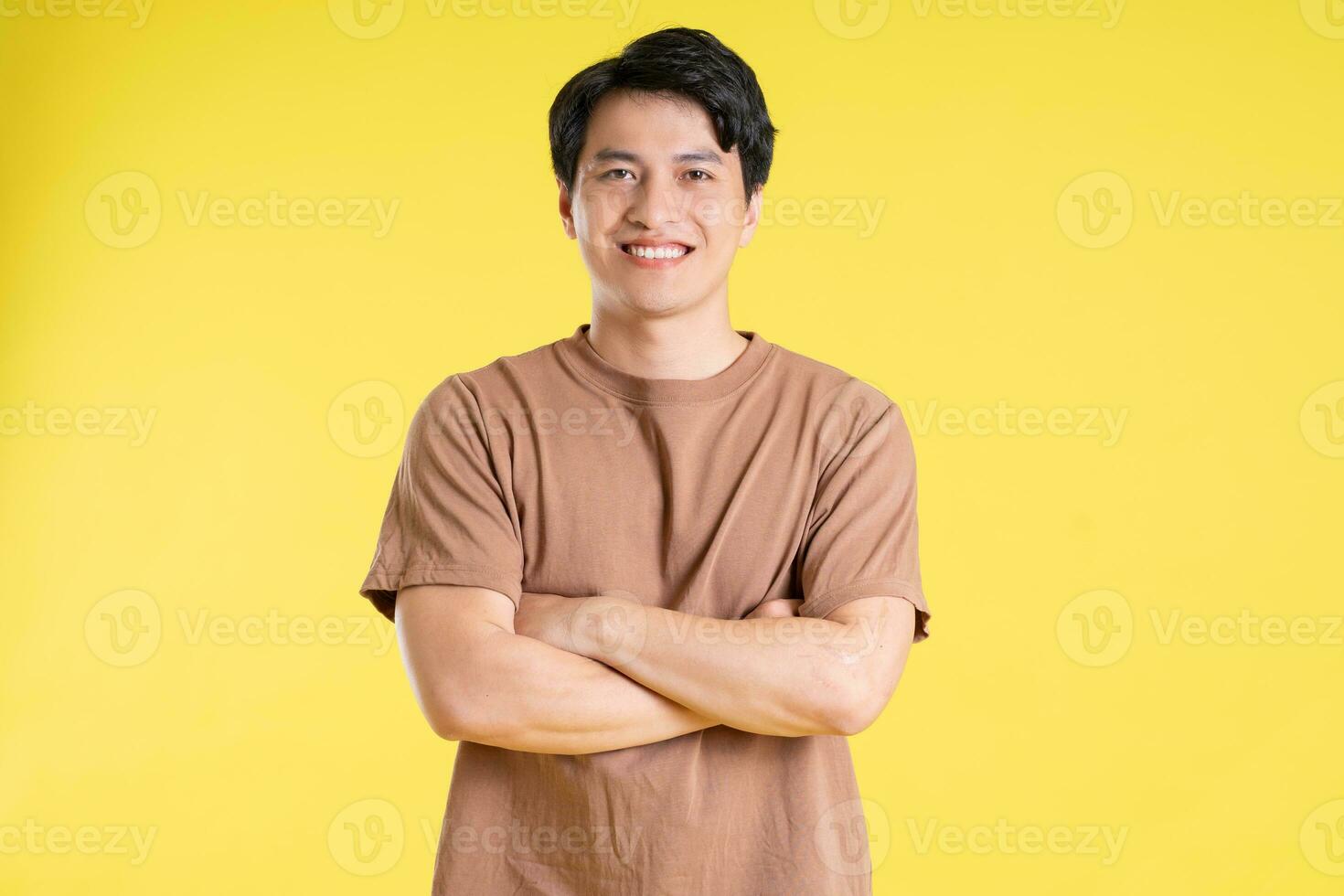 Portrait of asian man posing on yellow background photo