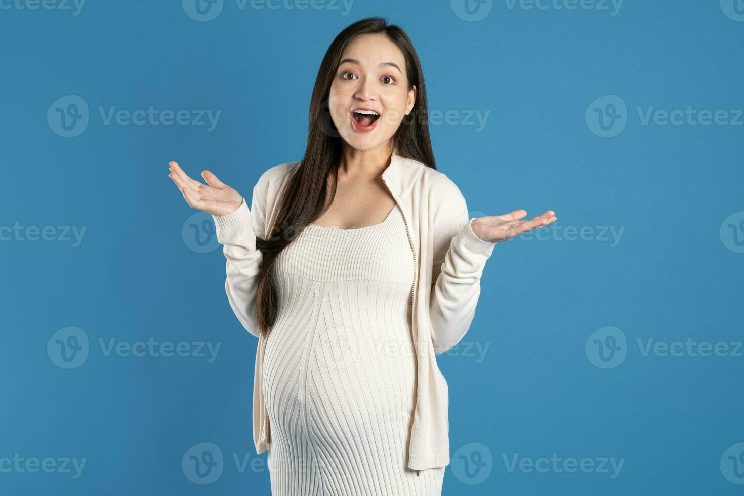 retrato de embarazada asiático mujer, aislado en azul antecedentes foto