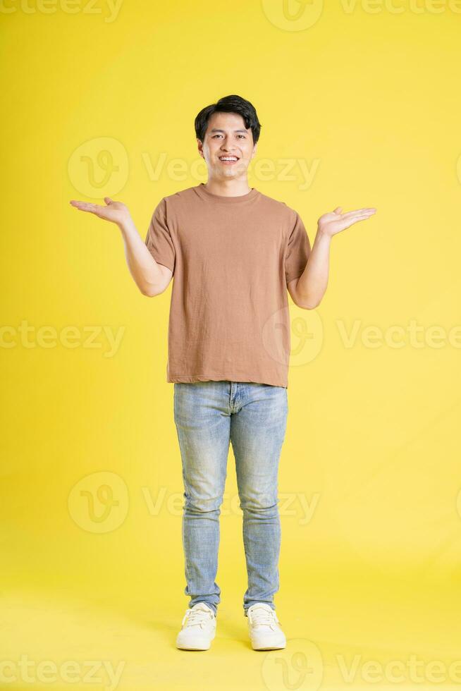 Portrait of asian man posing on yellow background photo
