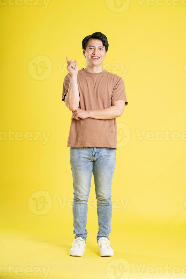 Portrait of asian man posing on yellow background photo