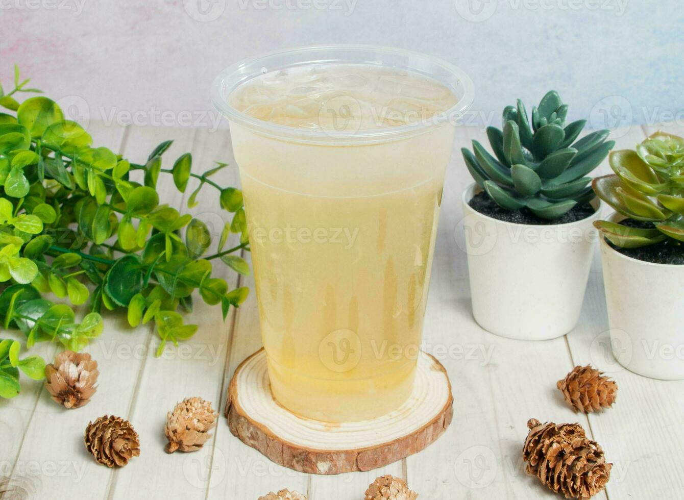 lemon and honey ice tea served om disposable glass isolated on wooden board top view of hong kong drink photo