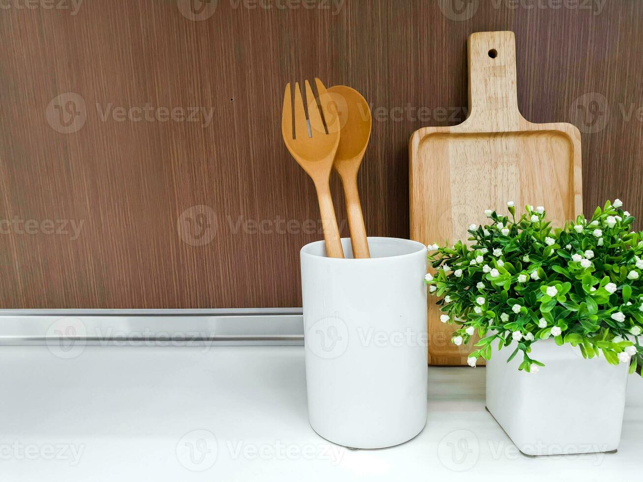 Wooden kitchenware and decorate small green plant in white ceramic vase on kitchen shelves and wooden wall background. photo