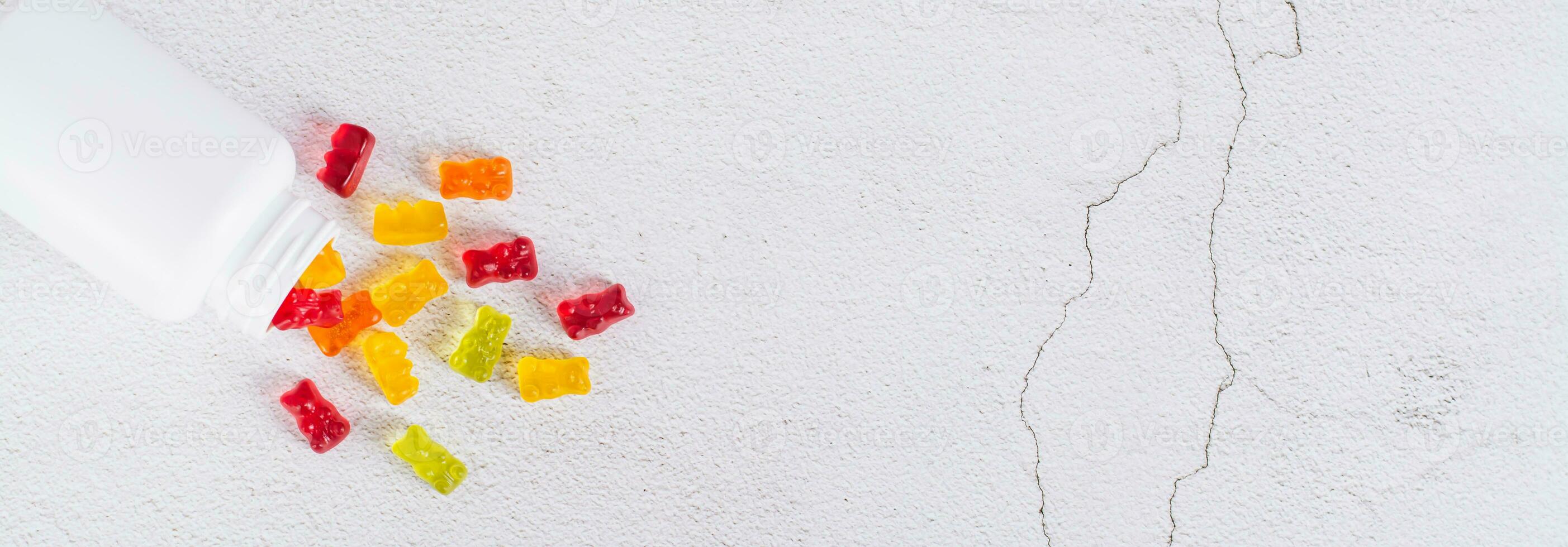 Bottle with gummy vitamin supplements in the shape of bears on the table top view web banner photo