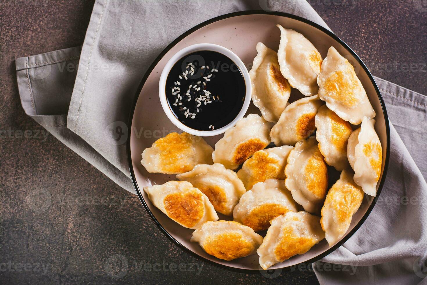 Close up of pan-fried dumplings with soy sauce on a plate on the table top view photo