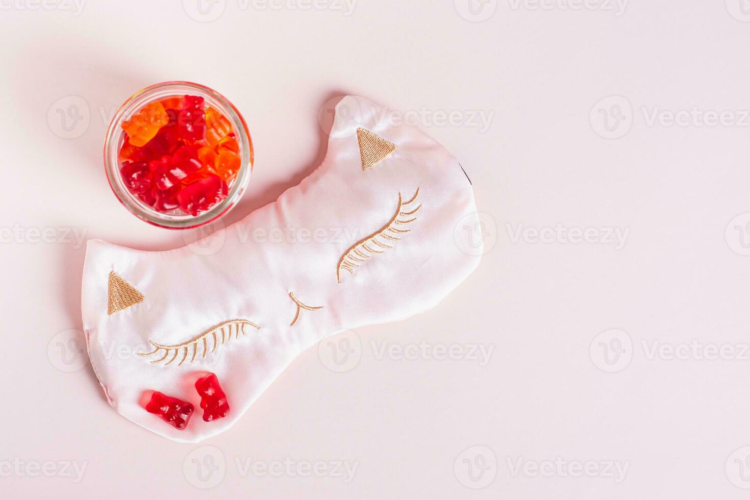 Chewable sleep vitamin supplements and mask on pink background top view photo