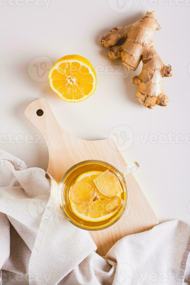 Organic healthy tea with ginger and lemon in a cup on the table top and vertical view photo