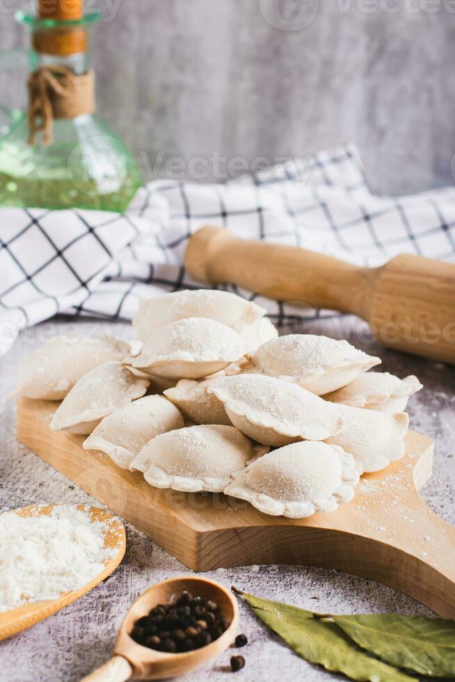 Homemade raw dumplings with meat on a cutting board on the table vertical view photo