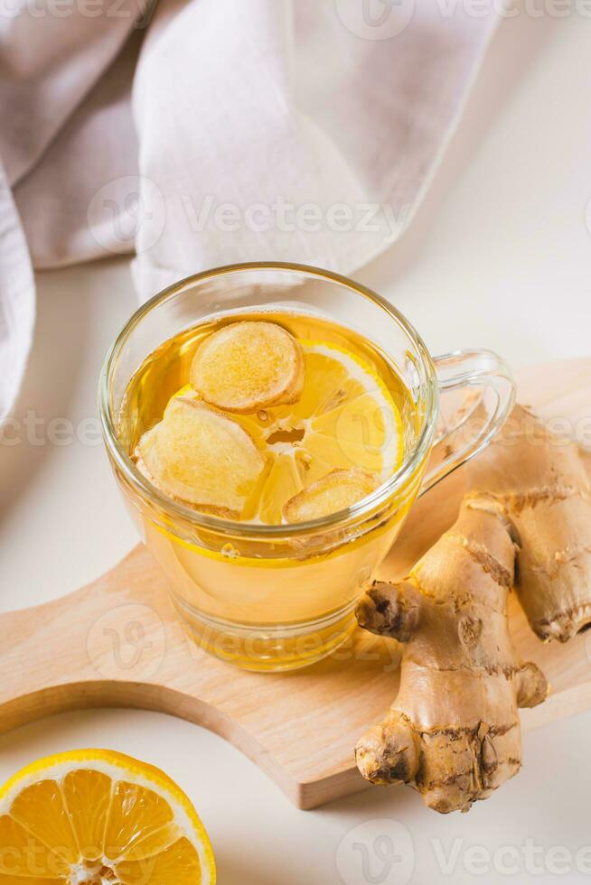 Organic healthy tea with ginger and lemon in a cup on the table vertical view photo