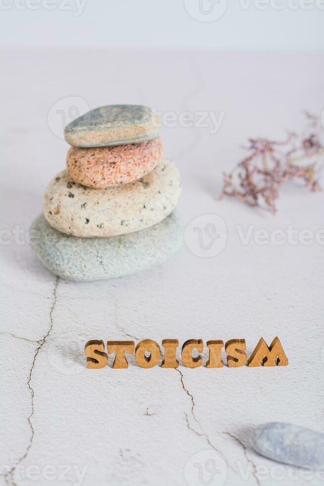 Concept of stoicism wooden letters on the background of a pyramid of stones  vertical view photo