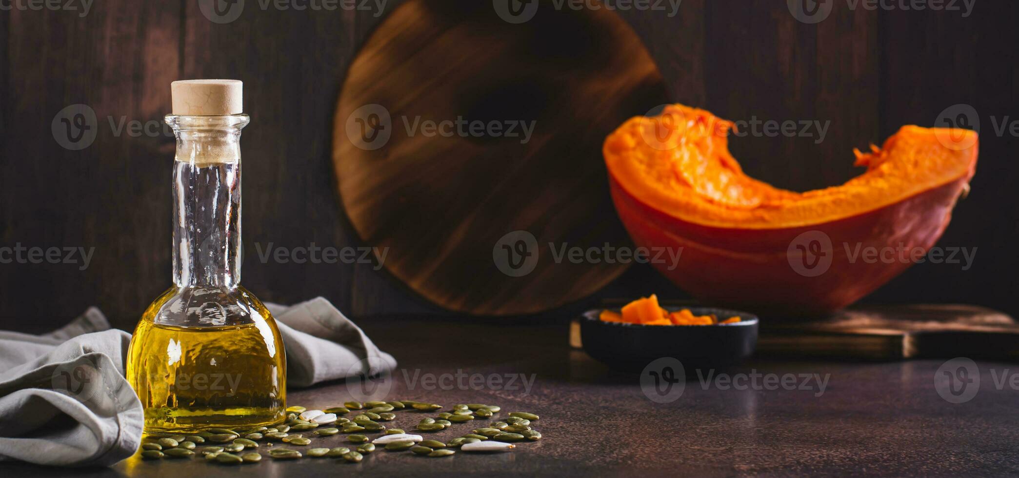 Fresh pumpkin seed oil and pumpkin pieces on the table web banner photo