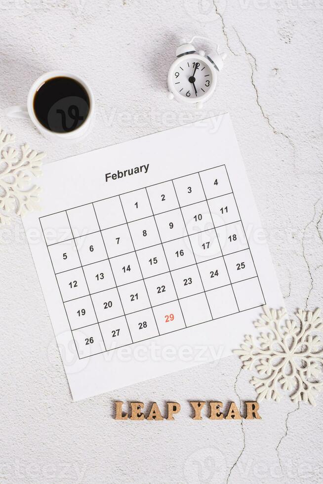 Leap year concept, calendar, coffee, alarm clock and text on light top and vertical view photo