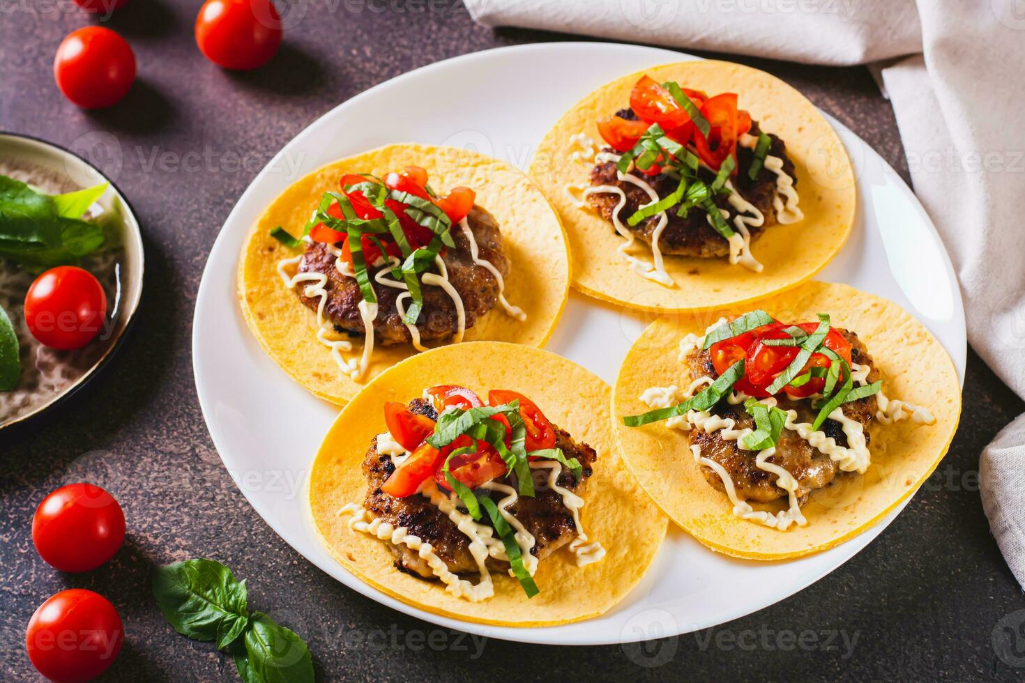 Smash Burger Tacos  with sauce, tomatoes and basil on a plate on the table photo