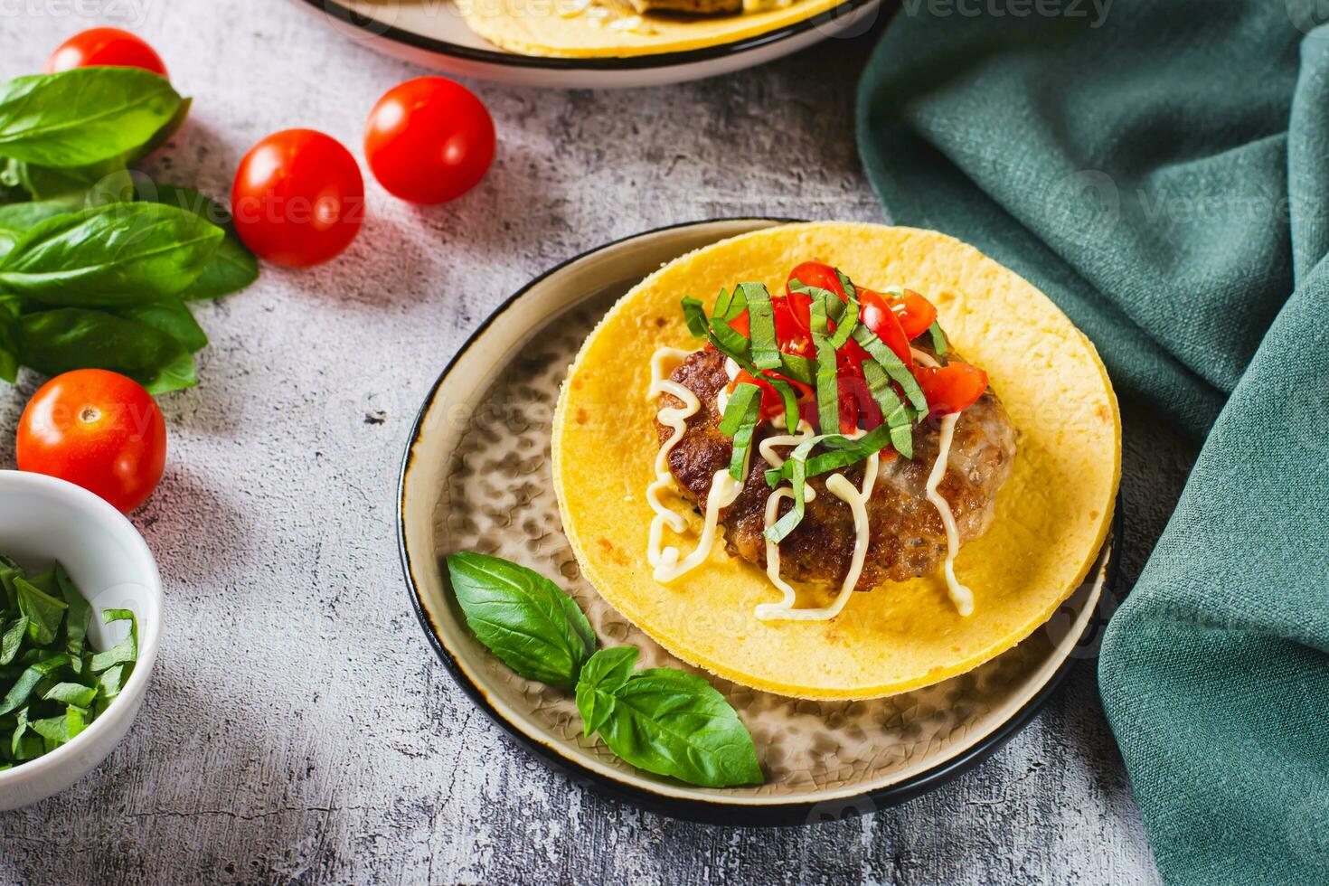 Smash Burger Tacos with beef patty, tomatoes and basil on a plate photo