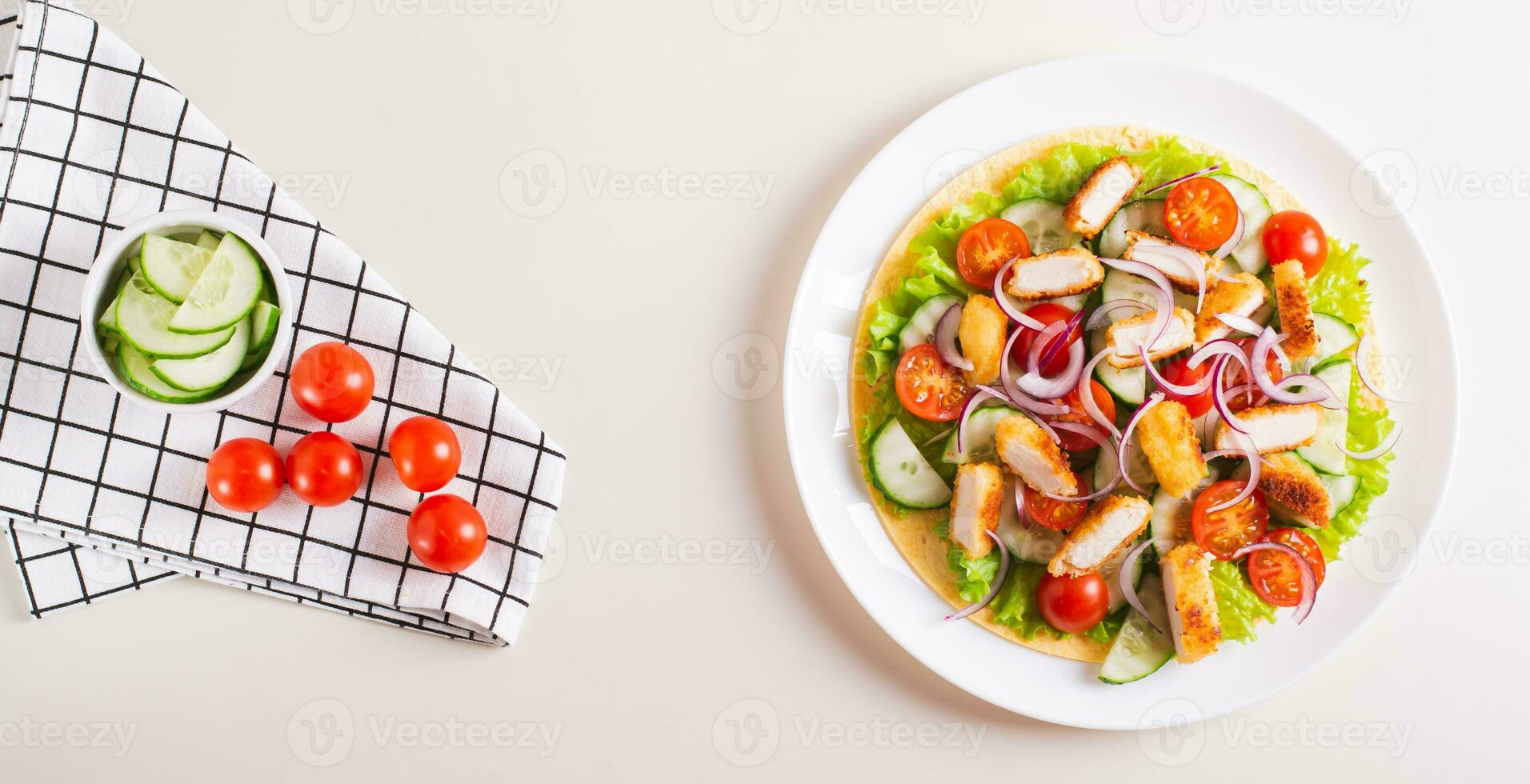 Tortilla with nuggets, vegetables and lettuce on a plate on the table top view web banner photo