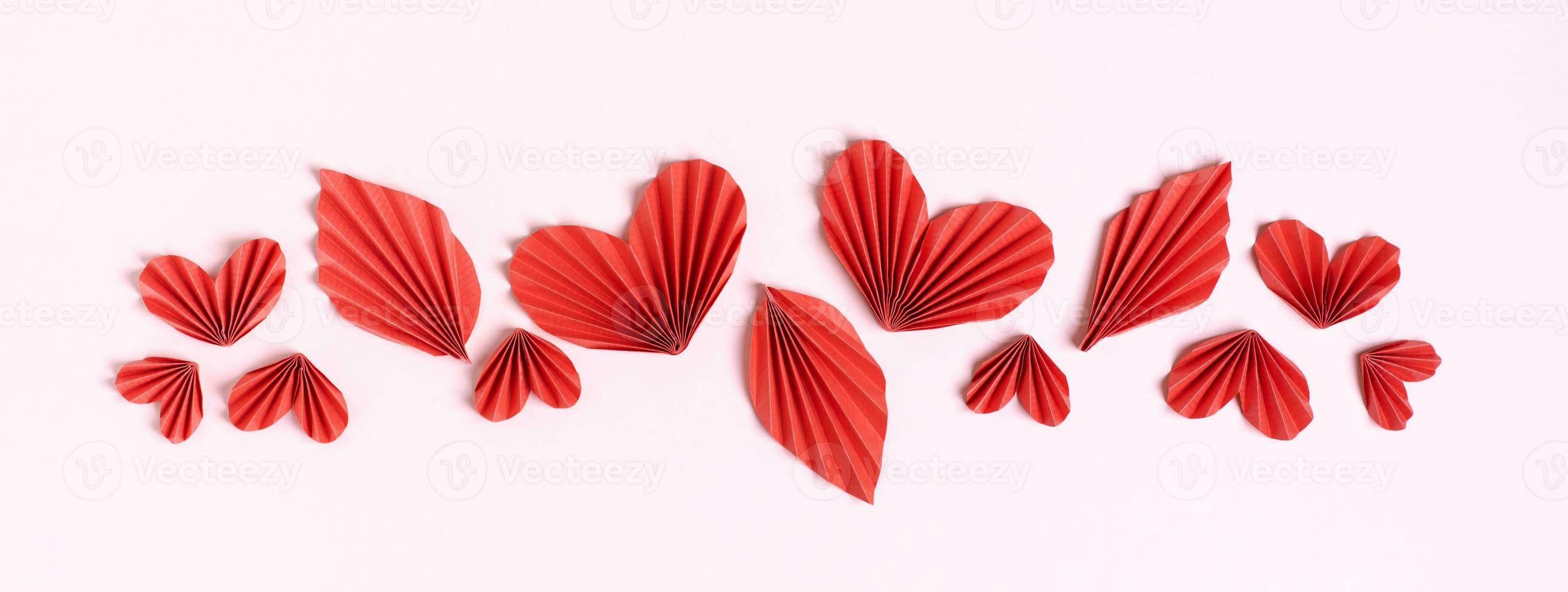 Web banner made of red curly hearts and leaves on a pink background top view photo