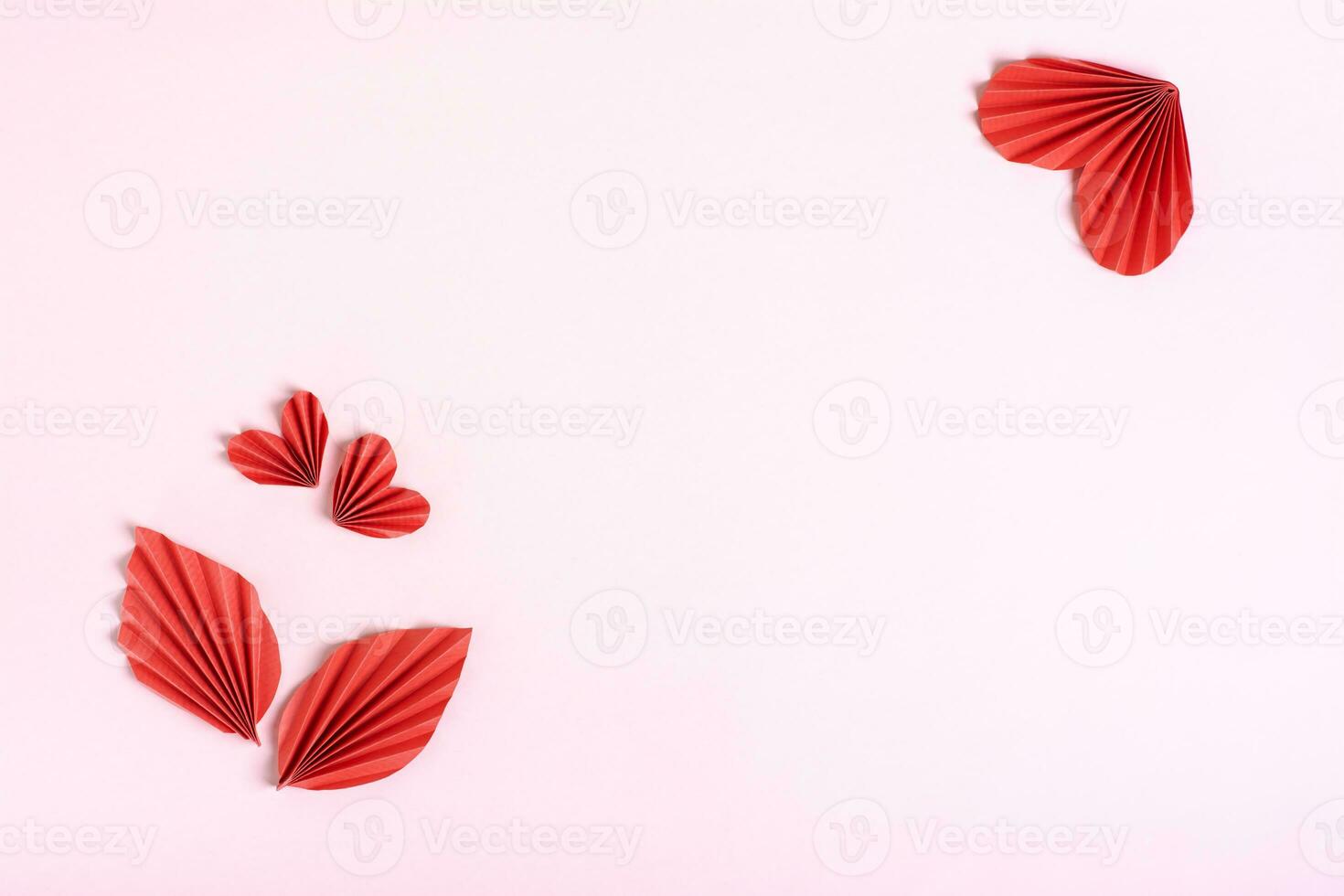Composition of folded red paper hearts and leaves on a pink background top view copy space photo