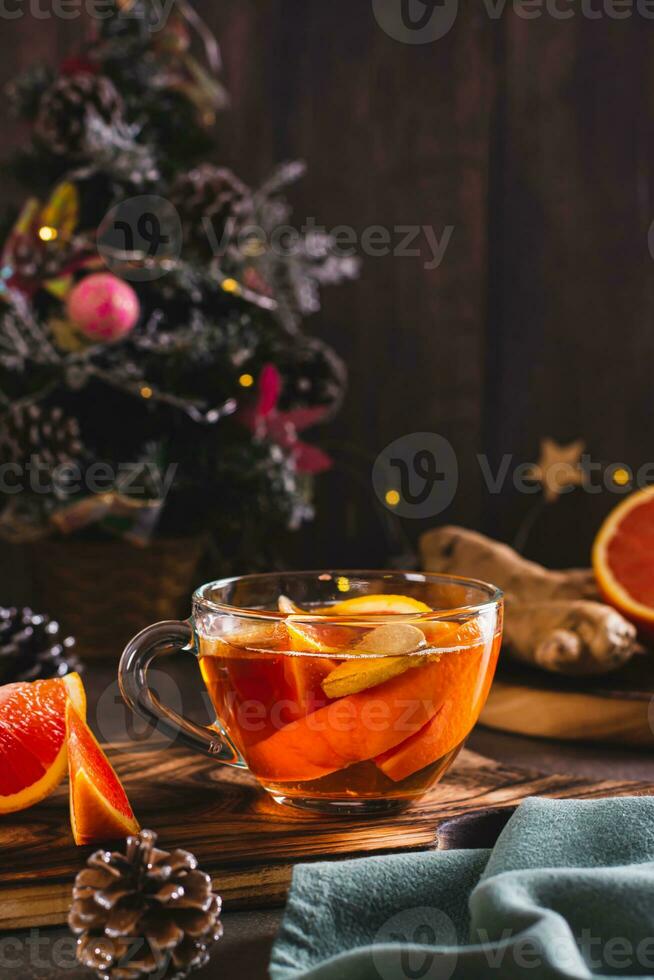 Fragrant tea with pieces of orange and ginger in a cup on the table vertical view photo