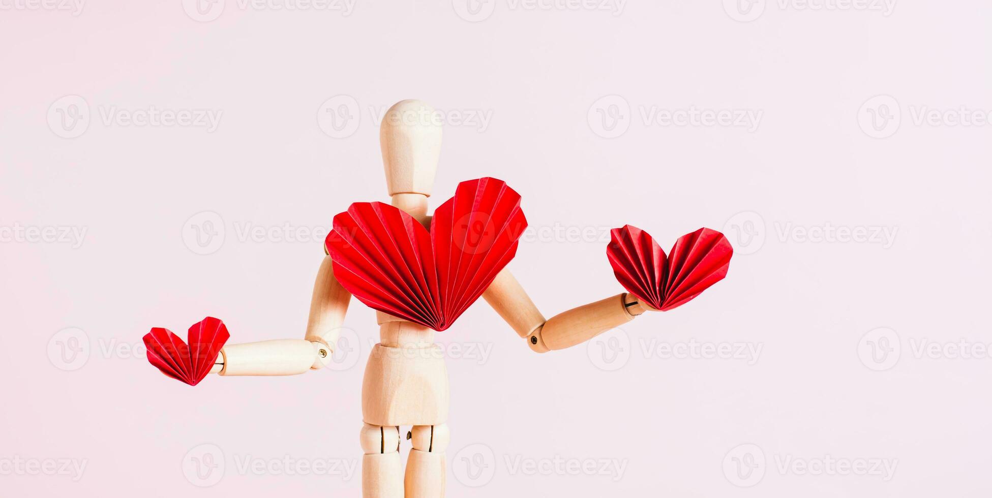 Wooden mannequin with red origami paper hearts on pink background web banner photo