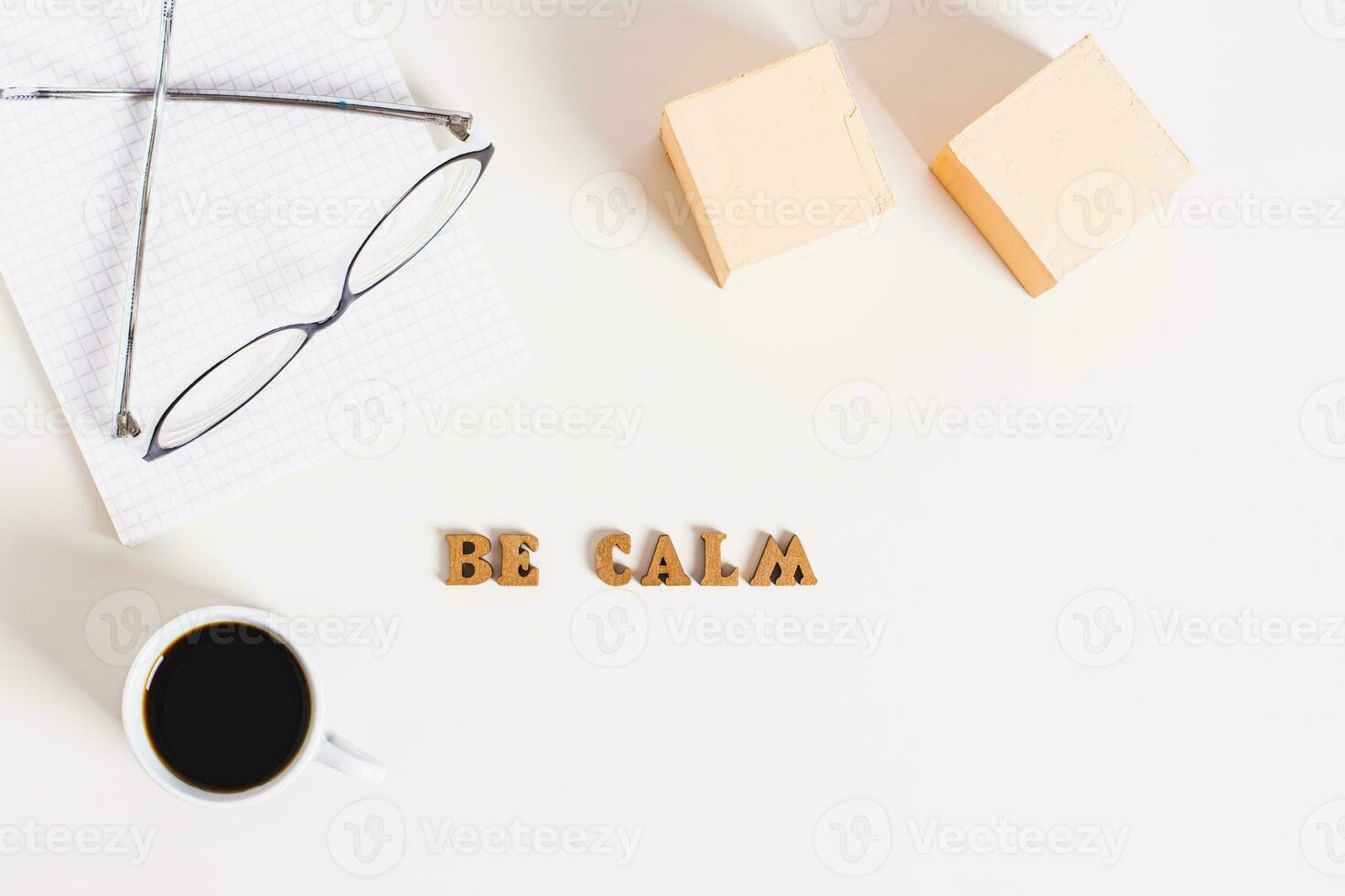 Concept be calm word, cup of coffee, notepad and glasses on a light background top view photo