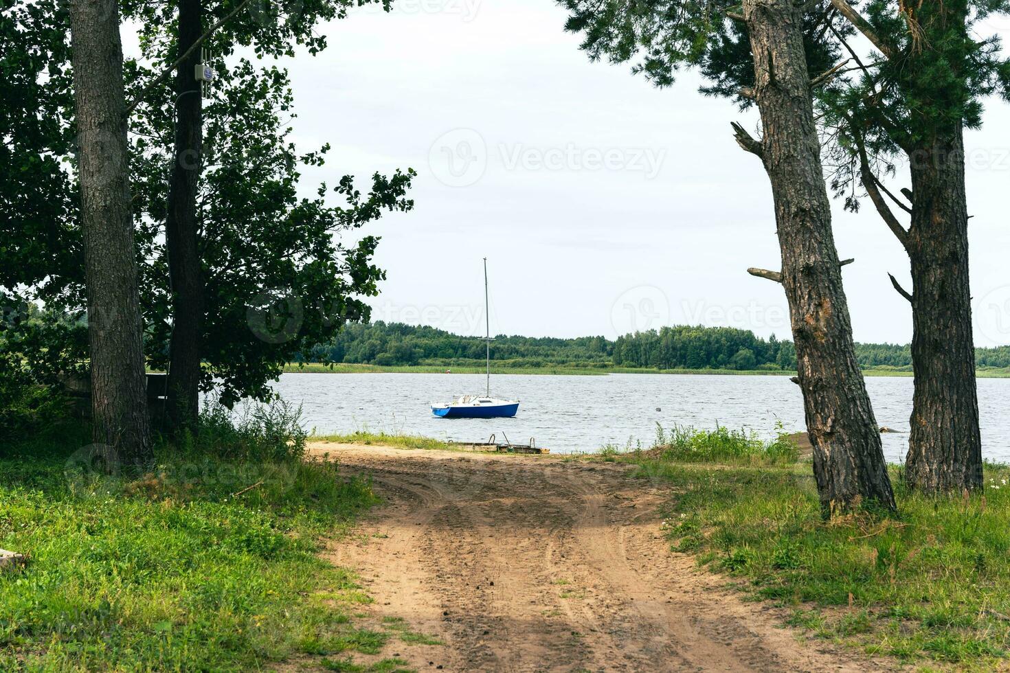 Scenic View of Small Sailboat on Lake with Dirt Road Leading to Water photo